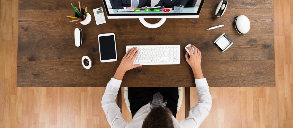High Angle View Of Young Businessman Videochatting With Senior Colleagues On Computer